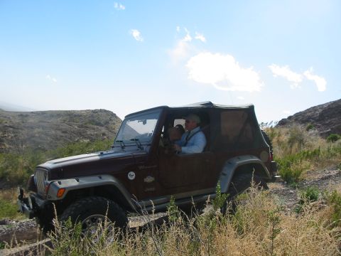 1996 Ford Bronco - Jeep Wrangler TJ driving on an off-road trail under a blue sky with scattered clouds.