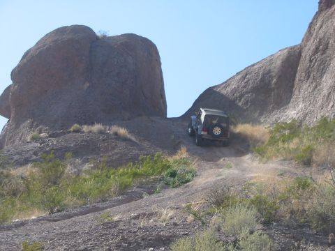 1996 Ford Bronco - Jeep Wrangler navigates a challenging off-road path in a desert landscape.