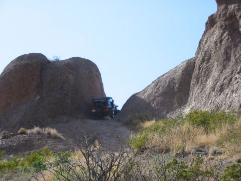 1996 Ford Bronco - A Jeep Wrangler navigates a rocky trail under a clear blue sky.