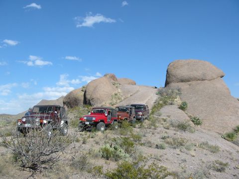 1996 Ford Bronco - Multiple Jeeps navigate a challenging off-road trail through a desert landscape.