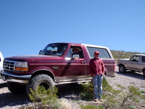 1996 Ford Bronco - Two men pose with their Ford Broncos in a dry, outdoor setting under a clear blue sky.