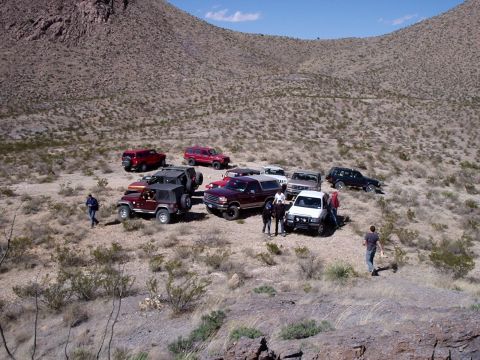 1996 Ford Bronco - A group of SUVs and trucks are gathered in a dry, hilly terrain under a clear blue sky.