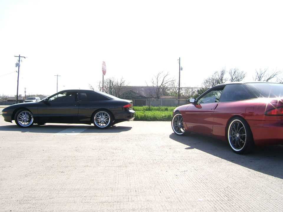 Two 1996 Ford Probe cars, one black and one red, parked on pavement
