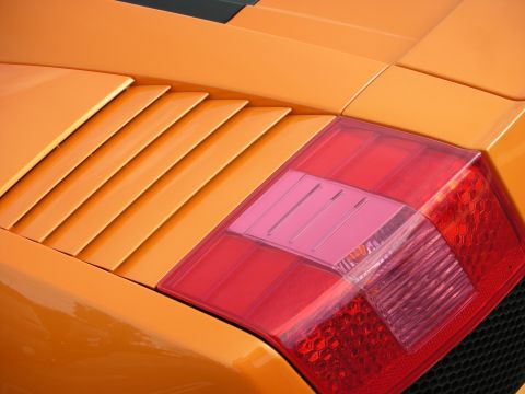 1998 Ford Crown Victoria - Close-up of an orange Lamborghini Gallardo's red rear taillight and the body-color slatted engine-deck vents.