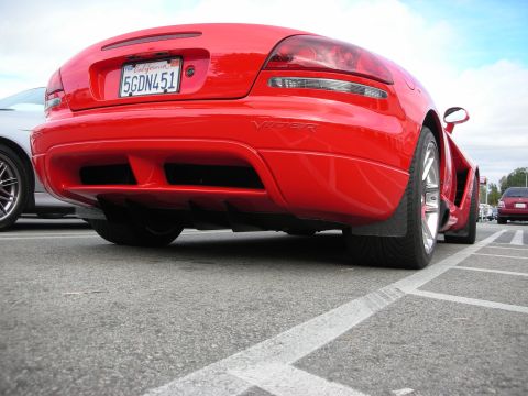 1998 Ford Crown Victoria - Low-angle rear view of a red Dodge Viper showing its rear diffuser, VIPER fender script and California plate in a parking lot.
