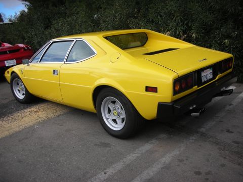 1998 Ford Crown Victoria - yellow Ferrari Dino 308 GT4 wedge coupe shown from the rear three-quarter, parked beside hedges.