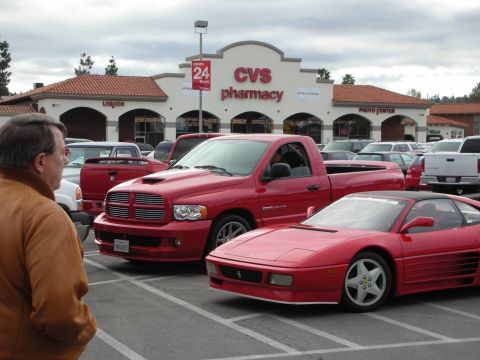 1998 Ford Crown Victoria - red Dodge Ram pickup and a red Ferrari 348 sit in a parking lot outside a CVS pharmacy as a man looks on.