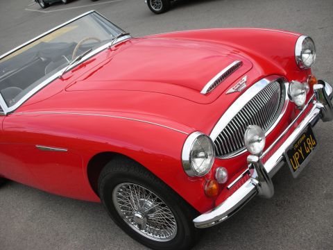 1998 Ford Crown Victoria - red Austin-Healey 3000 convertible shown from the front, with chrome grille, dual headlights, and wire wheels.