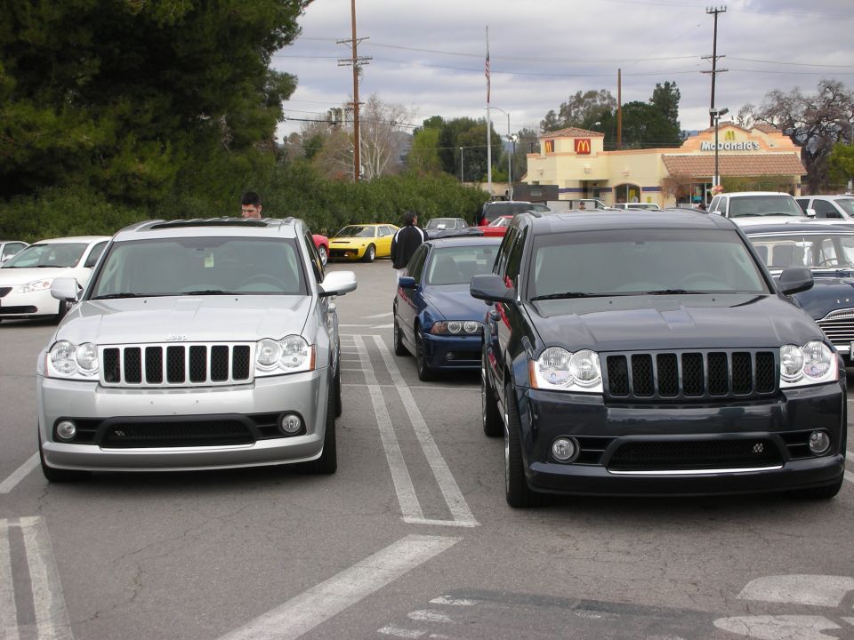 Silver and black Jeep Grand Cherokee SRT8 SUVs facing camera in lot