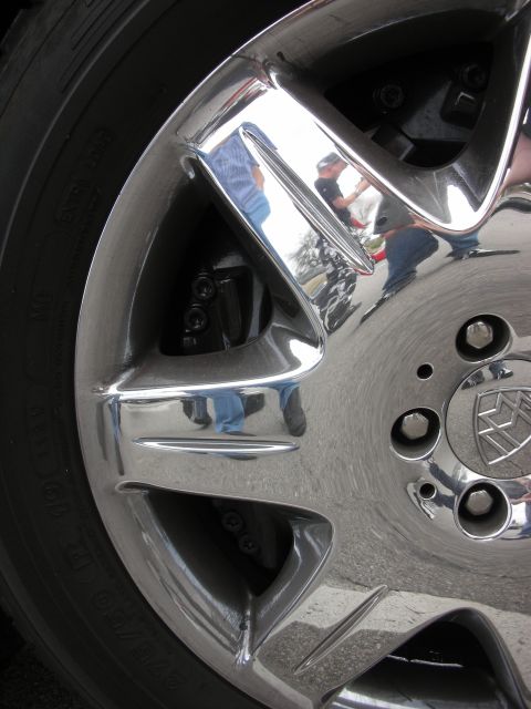 1998 Ford Crown Victoria - close-up of a chrome alloy wheel showing a crested center cap and visible disc brake behind the spokes.