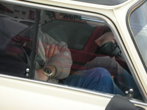1998 Ford Crown Victoria - person seated inside a cream classic Mini, seen through the side window wearing a watch and gray jacket.