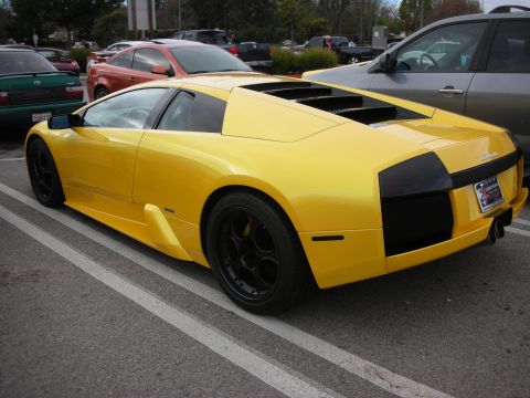 1998 Ford Crown Victoria - yellow Lamborghini Murcielago shown from the rear three-quarter, with black wheels, parked in a lot.