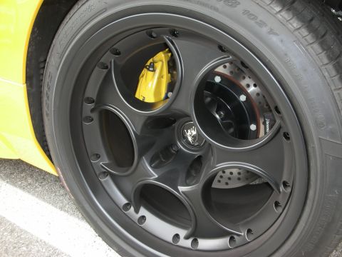1998 Ford Crown Victoria - close-up of a black split-spoke wheel with a yellow brake caliper and cross-drilled rotor on a yellow car.