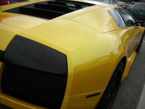 1998 Ford Crown Victoria - close-up of a yellow Lamborghini Murcielago's rear quarter, showing the side air intake and engine cover louvers.