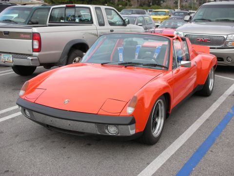 1998 Ford Crown Victoria - orange Porsche 914 targa with black trim and alloy wheels, parked front three-quarter in a lot beside trucks.