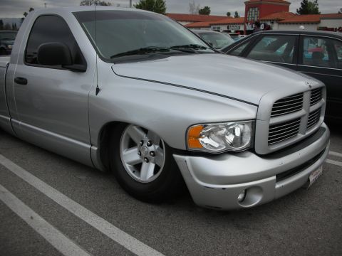 1998 Ford Crown Victoria - lowered silver Dodge Ram pickup is parked at an angle, showing its crosshair grille and five-spoke wheel.