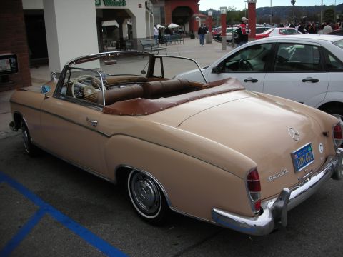 1998 Ford Crown Victoria - tan classic Mercedes-Benz convertible with its top down is parked outside a storefront, rear three-quarter view.