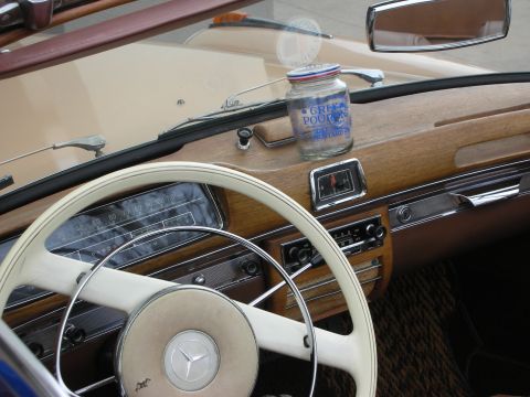 1998 Ford Crown Victoria - Interior of a vintage Mercedes-Benz showing wood dashboard, ivory steering wheel, and a jar resting on the dash.