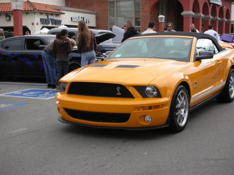 1998 Ford Crown Victoria - orange Ford Shelby Mustang convertible with its top up shows the Cobra grille badge at a busy car meet.