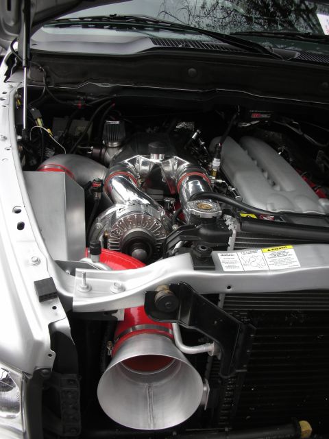 1998 Ford Crown Victoria - truck engine bay packed with a polished supercharger, red intake tubing, and chrome accessory pulleys.