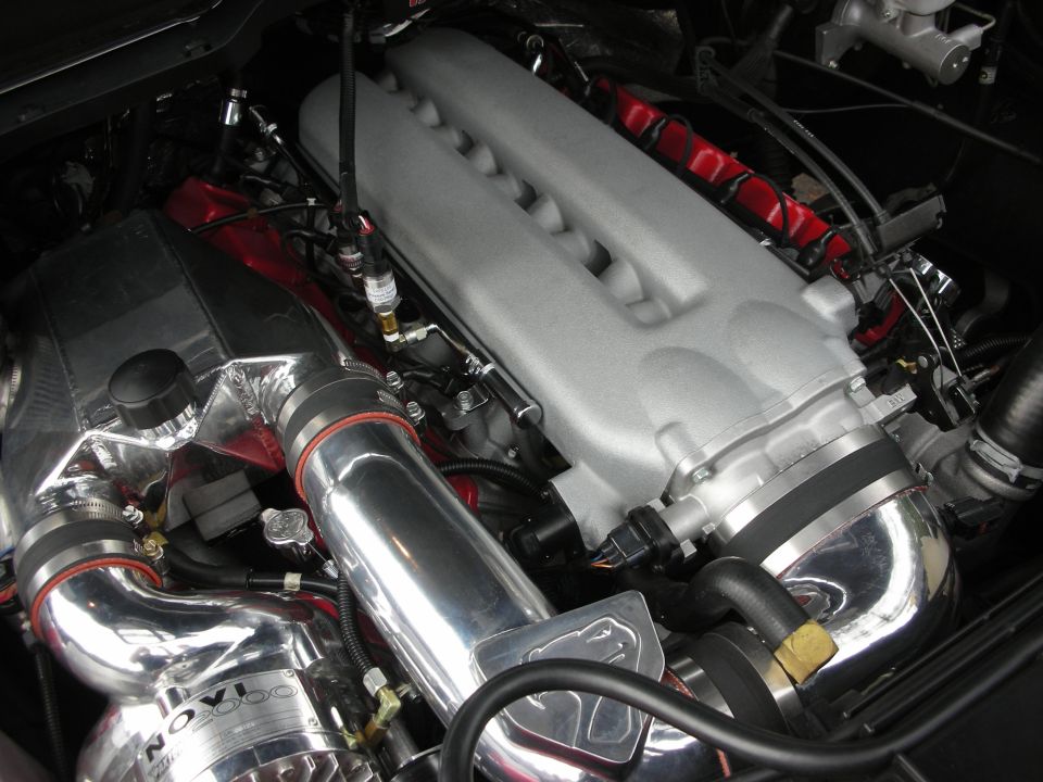 Close-up of a V10 engine intake manifold with polished piping and red plug wires