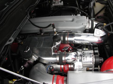 1998 Ford Crown Victoria - modified engine bay featuring polished intercooler piping, a supercharger, and a cone-style air filter.