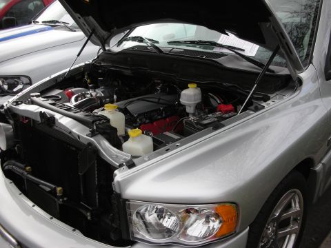 1998 Ford Crown Victoria - open hood of a silver Dodge Ram reveals its engine bay, radiator, and fluid reservoirs at a show.