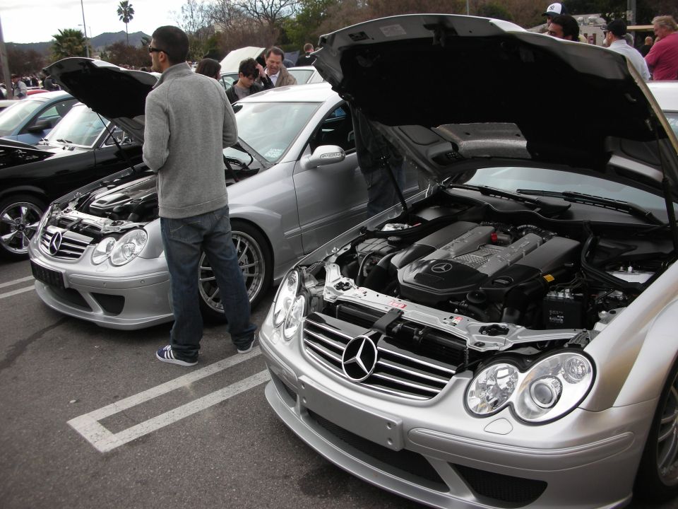 Two silver Mercedes-Benz CLK coupes with hoods open at a car meet