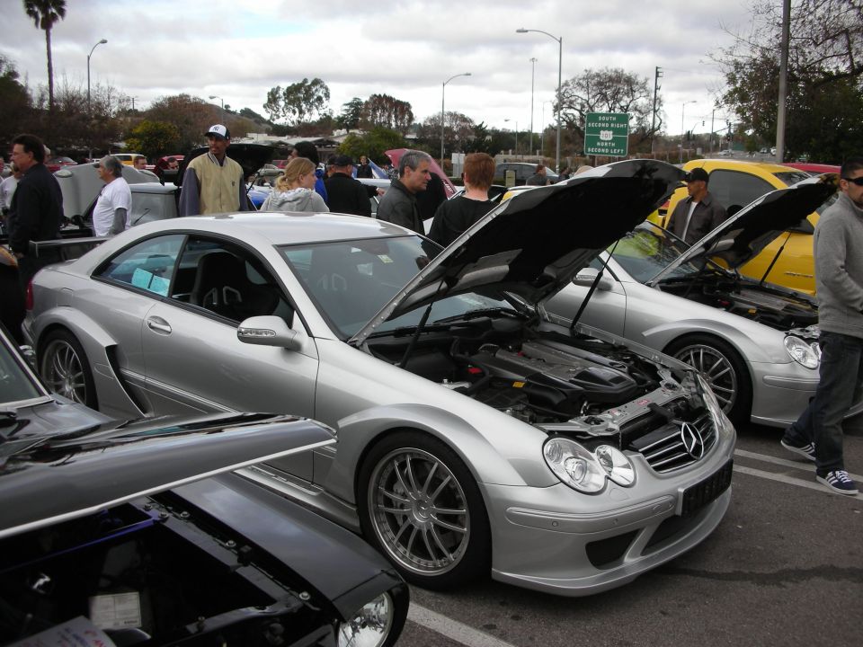 Silver Mercedes-Benz CLK coupes with hoods open among crowds at a car show