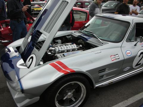 1998 Ford Crown Victoria - Front quarter of a silver number 2 vintage Corvette race car with raised hood, red stripe, and racing decals.