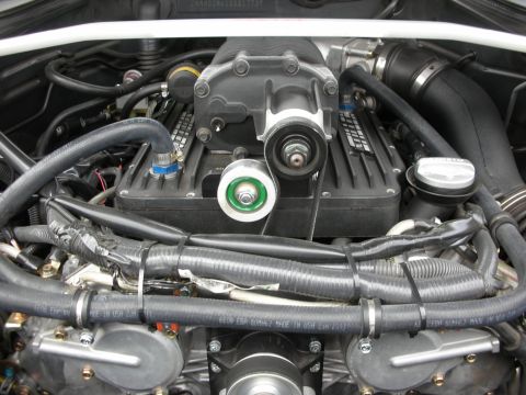 1998 Ford Crown Victoria - Close view of an engine bay dominated by a supercharger unit above coiled hoses and wiring harnesses.