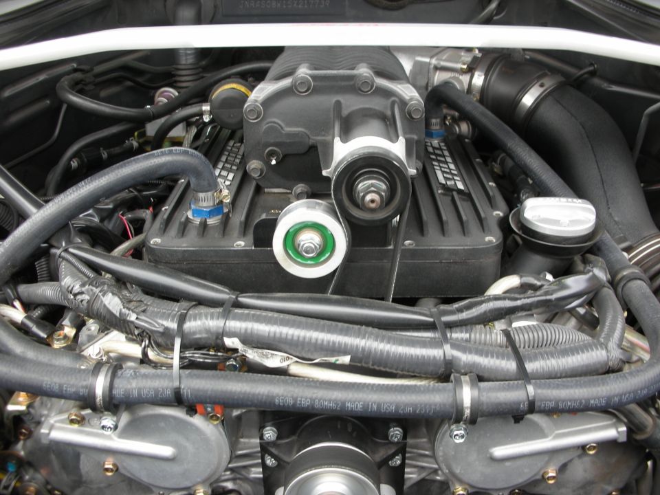 Engine bay showing a supercharger and braided wiring in a sports car
