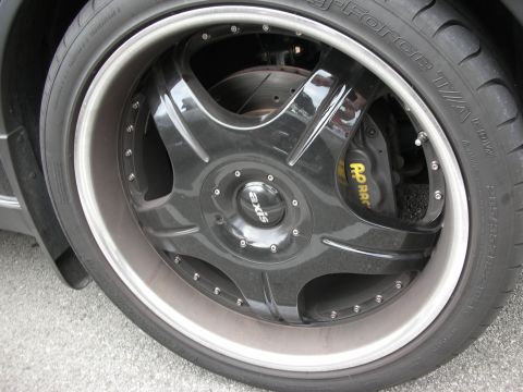 1998 Ford Crown Victoria - Close-up of a black multi-spoke Axis wheel with a red brake caliper and low-profile Toyo Proxes tire.