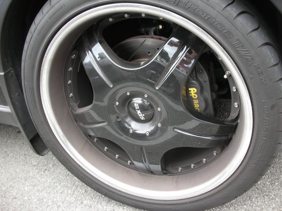 Black multi-spoke Axis wheel with low-profile tire and red brake caliper