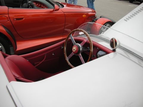 1998 Ford Crown Victoria - Cockpit of a white Jaguar roadster with red interior and wood-rimmed wheel, parked next to a red Plymouth Prowler.