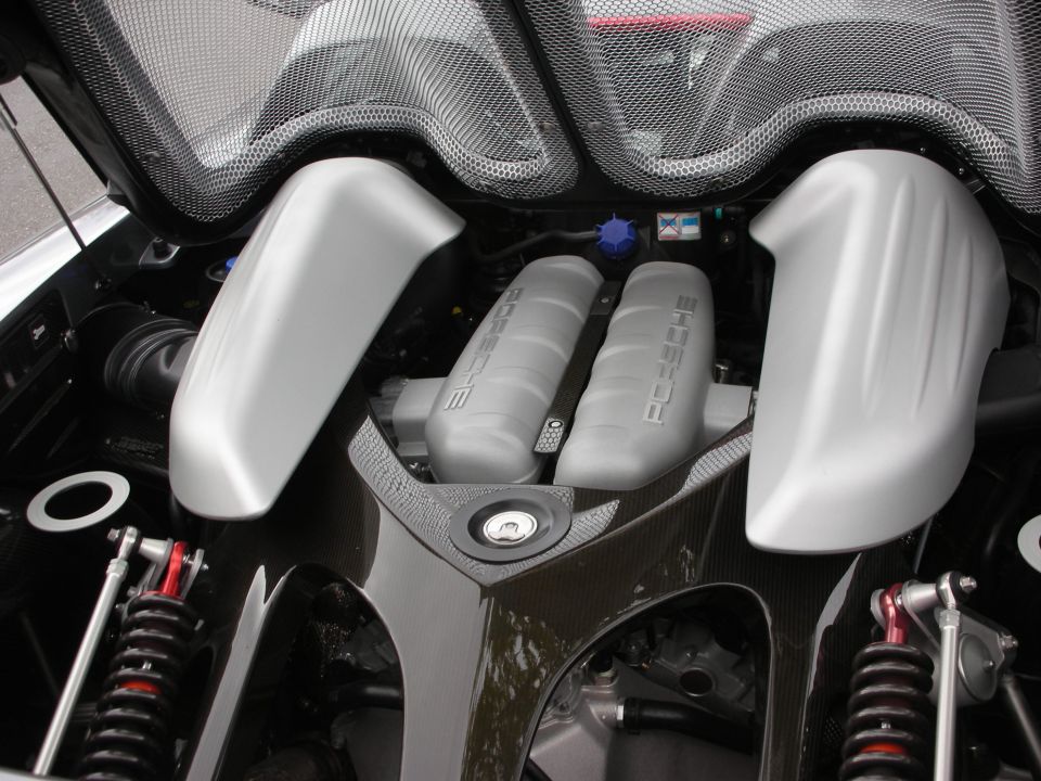 Porsche engine bay with silver intake covers and exposed rear suspension