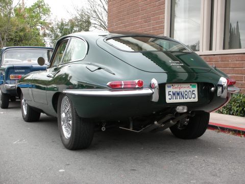 1998 Ford Crown Victoria - dark green Jaguar E-Type fixed-head coupe seen from the rear three-quarter with wire wheels and a California license plate.