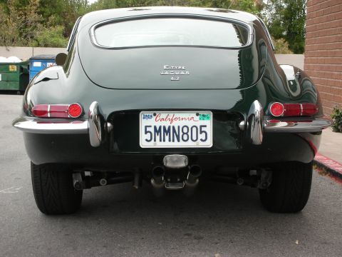1998 Ford Crown Victoria - Direct rear view of a dark green Jaguar 4.2 coupe showing round taillights, dual exhaust, and a California plate.