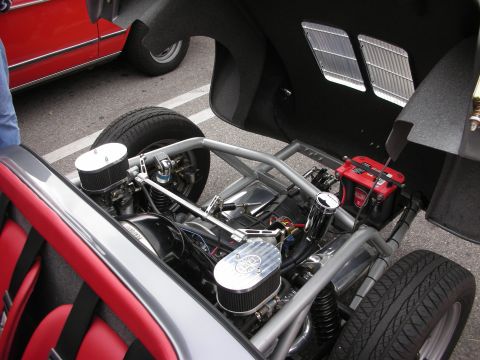 1998 Ford Crown Victoria - open rear of a roadster revealing a tubular space frame, twin chrome air filters and a battery on the chassis.