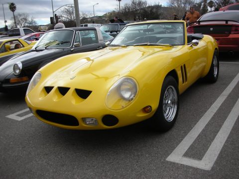 1998 Ford Crown Victoria - yellow Ferrari 250 GTO-style coupe with triple front nose vents and chrome wire wheels parked at a car show.