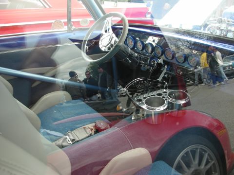 1998 Ford Crown Victoria - custom car interior seen through glass showing a chromed dash with rows of round gauges and blue-and-gray seats.