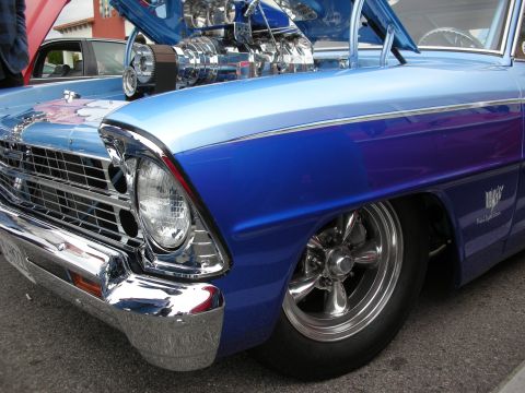 1998 Ford Crown Victoria - chrome grille, single round headlight and blue-to-purple painted front fender of a classic car with mag wheels at a show.