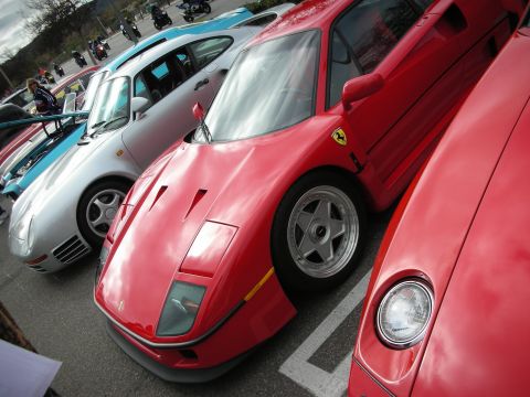 1998 Ford Crown Victoria - red Ferrari F40 parked between a silver Porsche 959 and another red Ferrari at an outdoor exotic-car gathering.