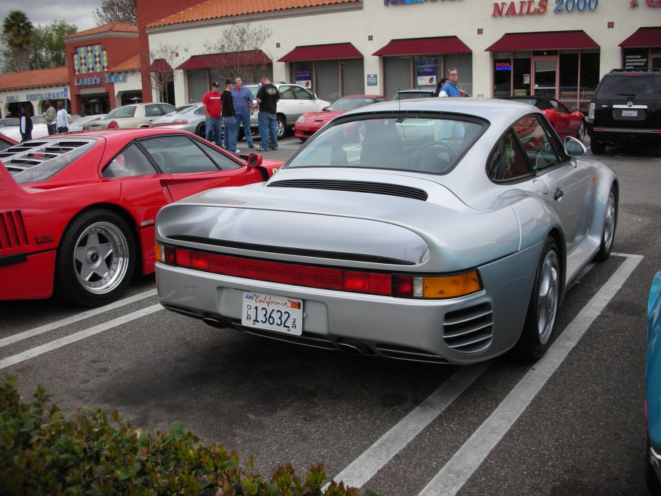 Rear of a silver Porsche 959 with California plate beside a red Ferrari F40