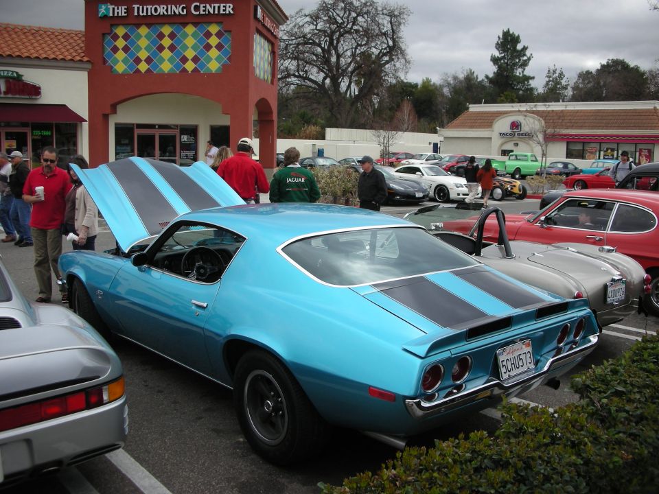 Blue 1970 Camaro with black stripes parked at a strip-mall car meet