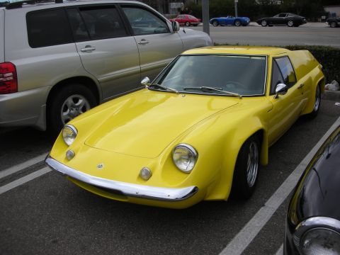 1998 Ford Crown Victoria - bright yellow Lotus Europa coupe with chrome bumper and pop-up-style headlights is parked in a lot beside a silver SUV.