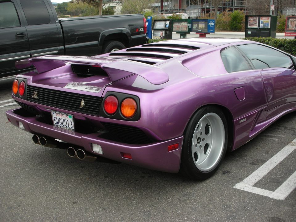 Purple Lamborghini Diablo rear three-quarter parked beside a pickup truck