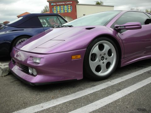 1998 Ford Crown Victoria - Close front three-quarter of a purple Lamborghini Diablo highlighting its low nose, pop-up headlight area and multi-spoke wheel.