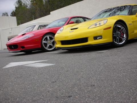 1998 Ford Crown Victoria - Low-angle shot of a yellow Chevrolet Corvette Z06 front end, with chrome five-spoke wheel and red brake caliper, beside a red Ferrari.