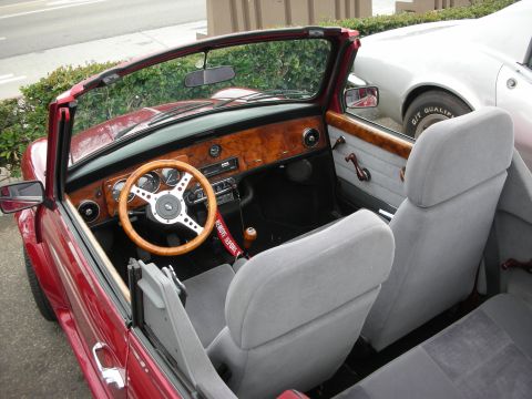 1998 Ford Crown Victoria - Open-top interior of a red classic Mini showing a burl-wood dashboard, wood-rimmed steering wheel and gray cloth seats.